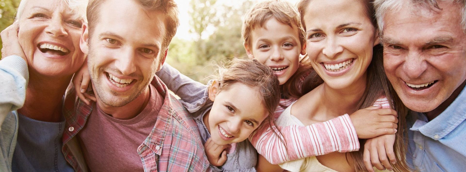 Eine lächelnde Familie mit Kindern und Erwachsenen, die zusammen Freude und Glück ausstrahlen